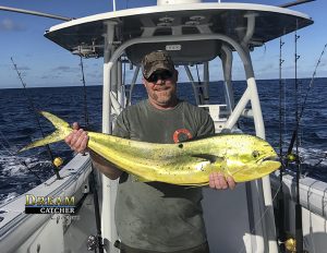 Deep sea fishing angler holds up a nice dolphin mahi-mahi he caught fishing Key West